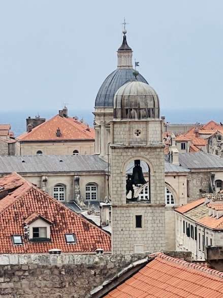 In the middle of Dubrovnik city, stands a gray granite bell tower with figure ringing the bell